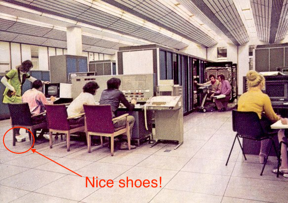 “You know Simon once we’ve debugged this code, we’re going straight down the discotheque to dance the night away to that groovy new hit record by those local Manchester lads the Bee Gees. How does it go? Night fever, night fever, we know how to show it.” The people in the picture are, from left to right, Pat McKissack (wearer of fantastic shoes), Simon Lavington, Gordon Frank, Roland Ibbett, Peter Whitehead, Tony Whitehouse and Lynne Plant (seated at the system performance monitor). The MU5 console is in the foreground with the big machine in the background. The picture is probably taken sometime between about 1972 and 1978, but we’ve gone for 1978 so that we can make gratuitous references to seventies disco music. See the original unadulterated image via Simon Lavington and the Computer Conservation Society. (Lavington 2008)