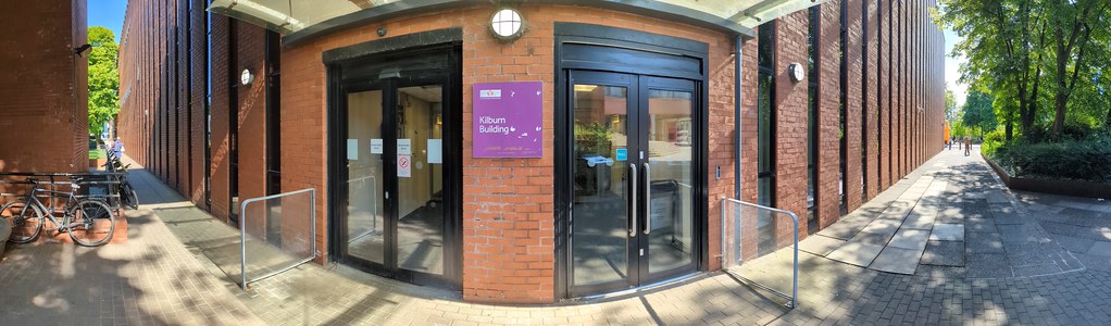 A panoramic picture of the North entrance of the Kilburn building with the Oxford Road on the right hand side of the picture.
