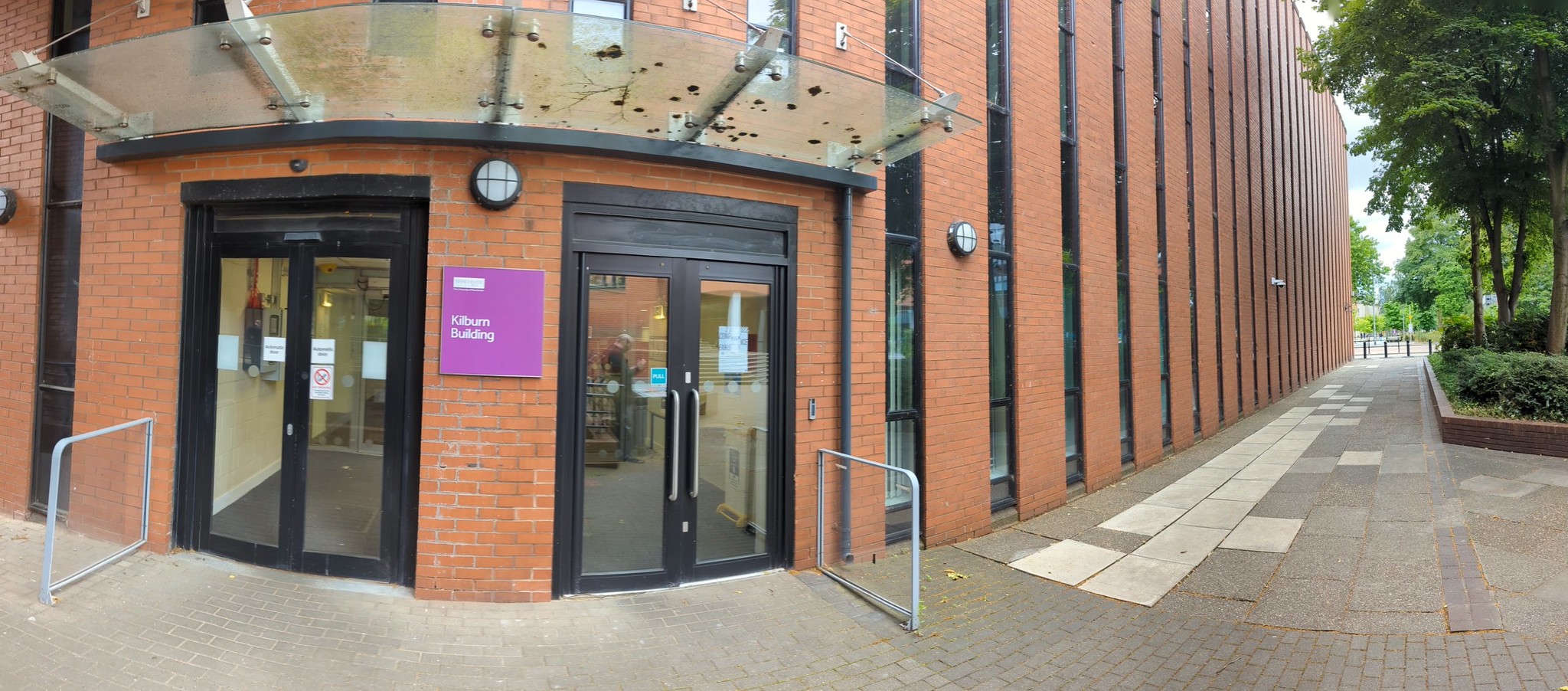 A panoramic picture of the North entrance of the Kilburn building with the Oxford Road on the right hand side of the picture.