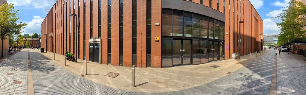 A panoramic picture of the South entrance of the Kilburn building on Wilton Street with the Oxford Road on the left and the Alan Turing Building on the right hand side of the picture.